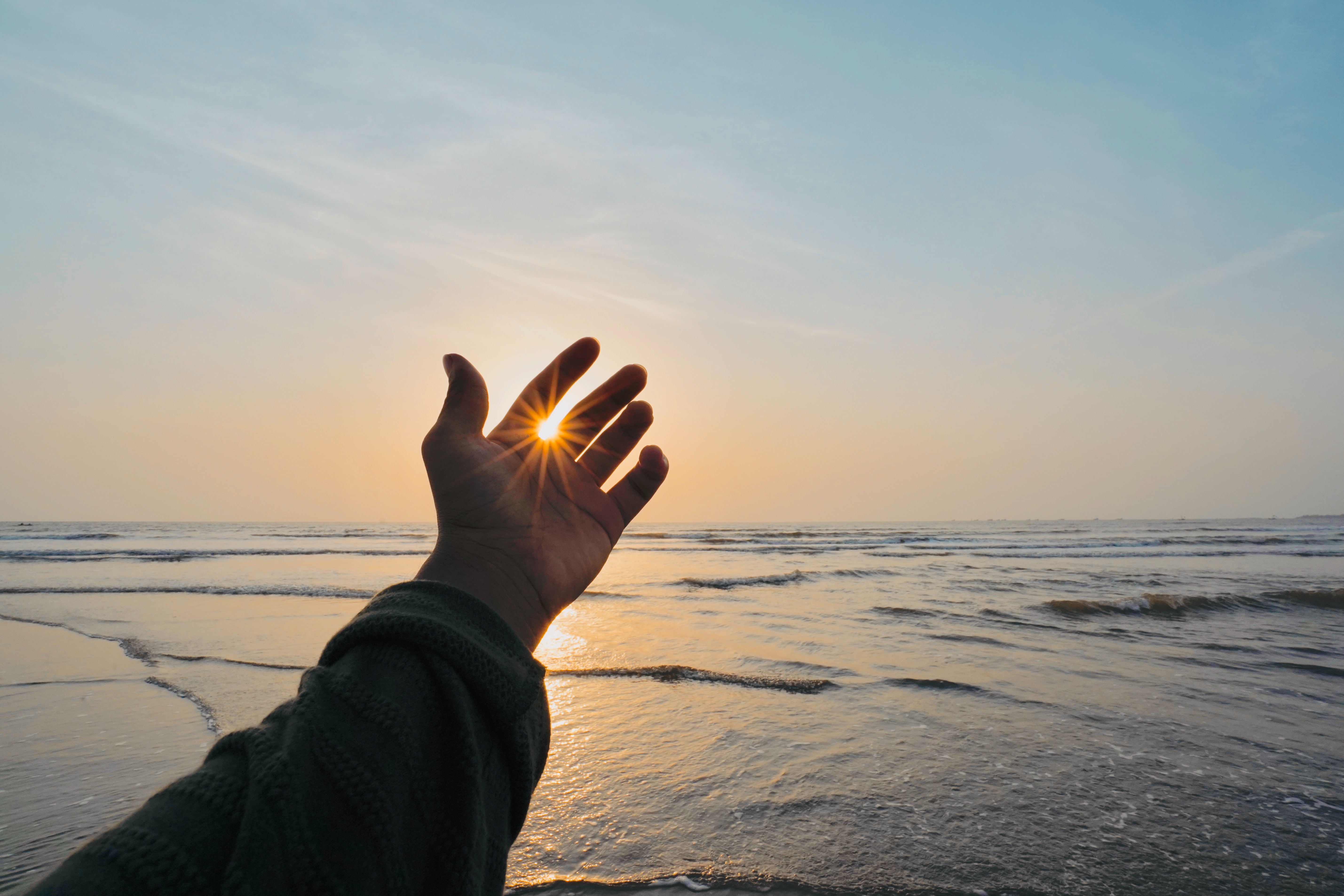 Free download wallpaper Sun, Hand, Miscellanea, Rays, Beams, Fingers, Sea, Miscellaneous, Waves on your PC desktop