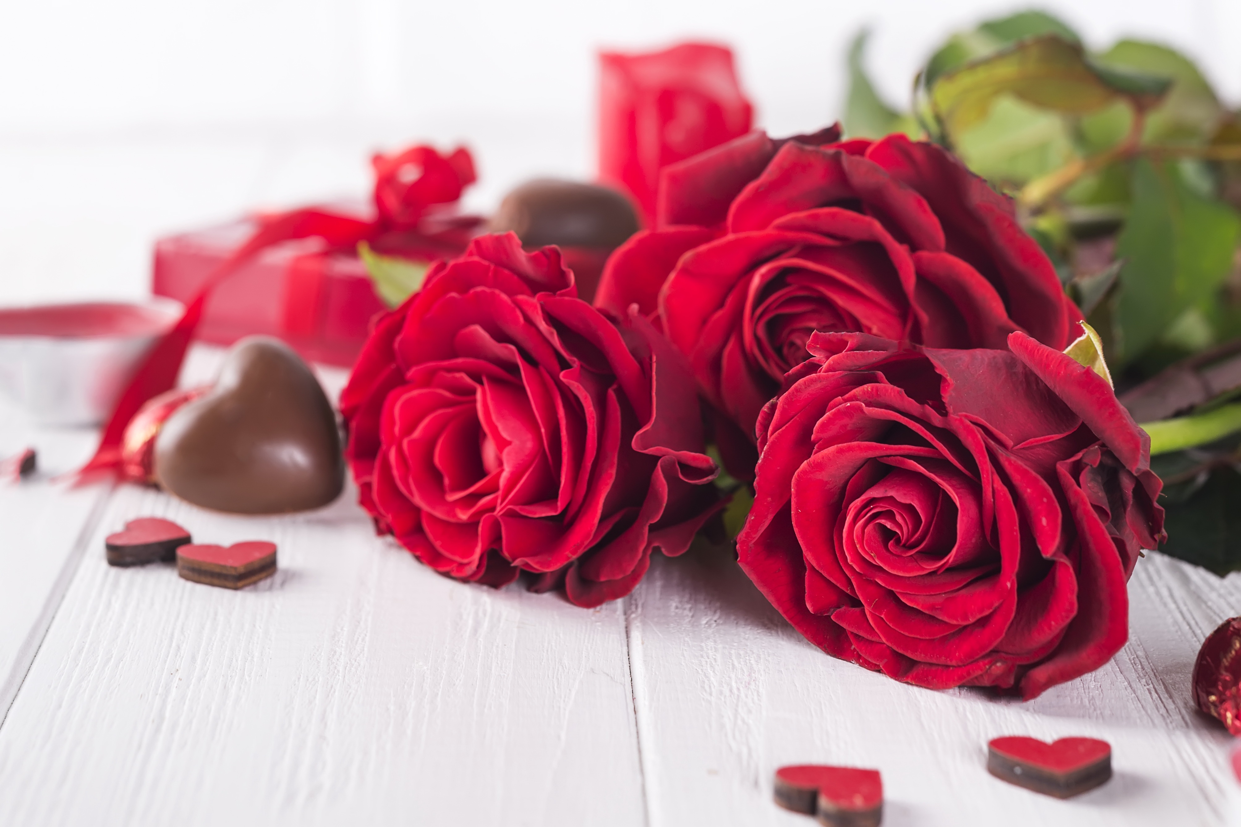 Цветы и шоколадка. Красные розы. Романтические цветы. Розы лежат на столе. Красные розы фон.