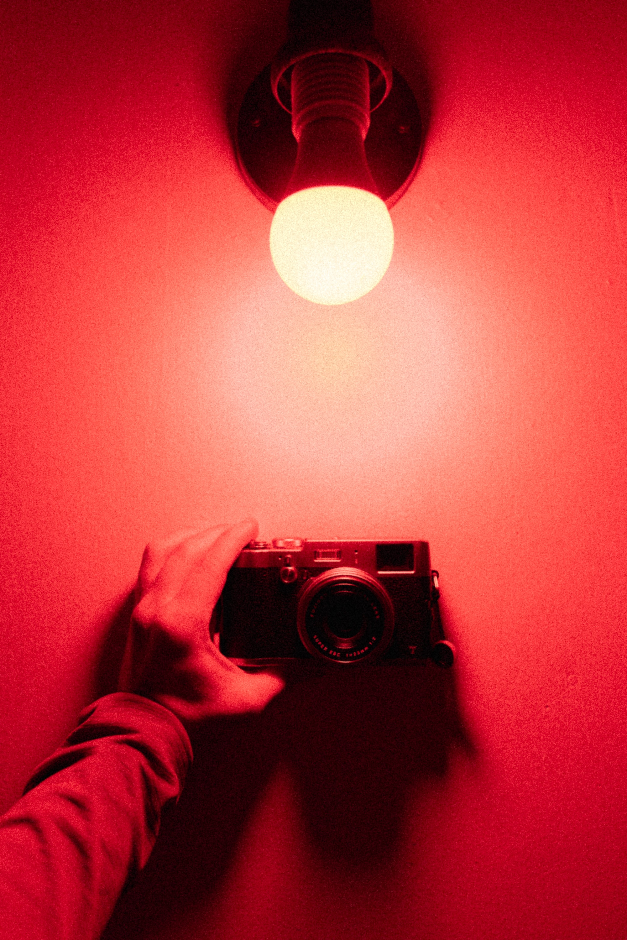 Скачать картинку Фотоаппарат, Лампочка, Разное, Красный, Рука, Свет в телефон бесплатно.